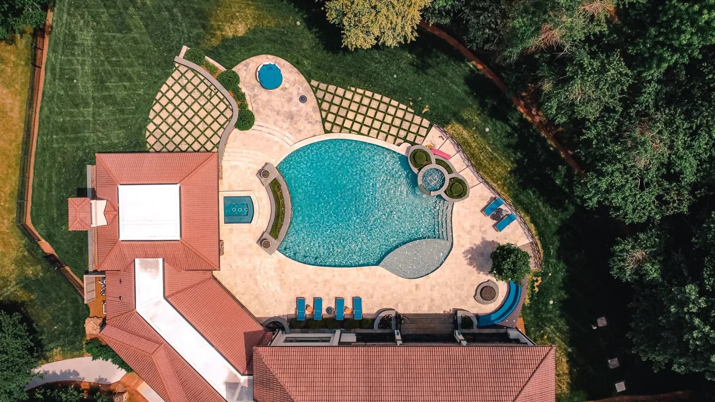 Aerial view of a backyard pool, spa, and surrounding landscape